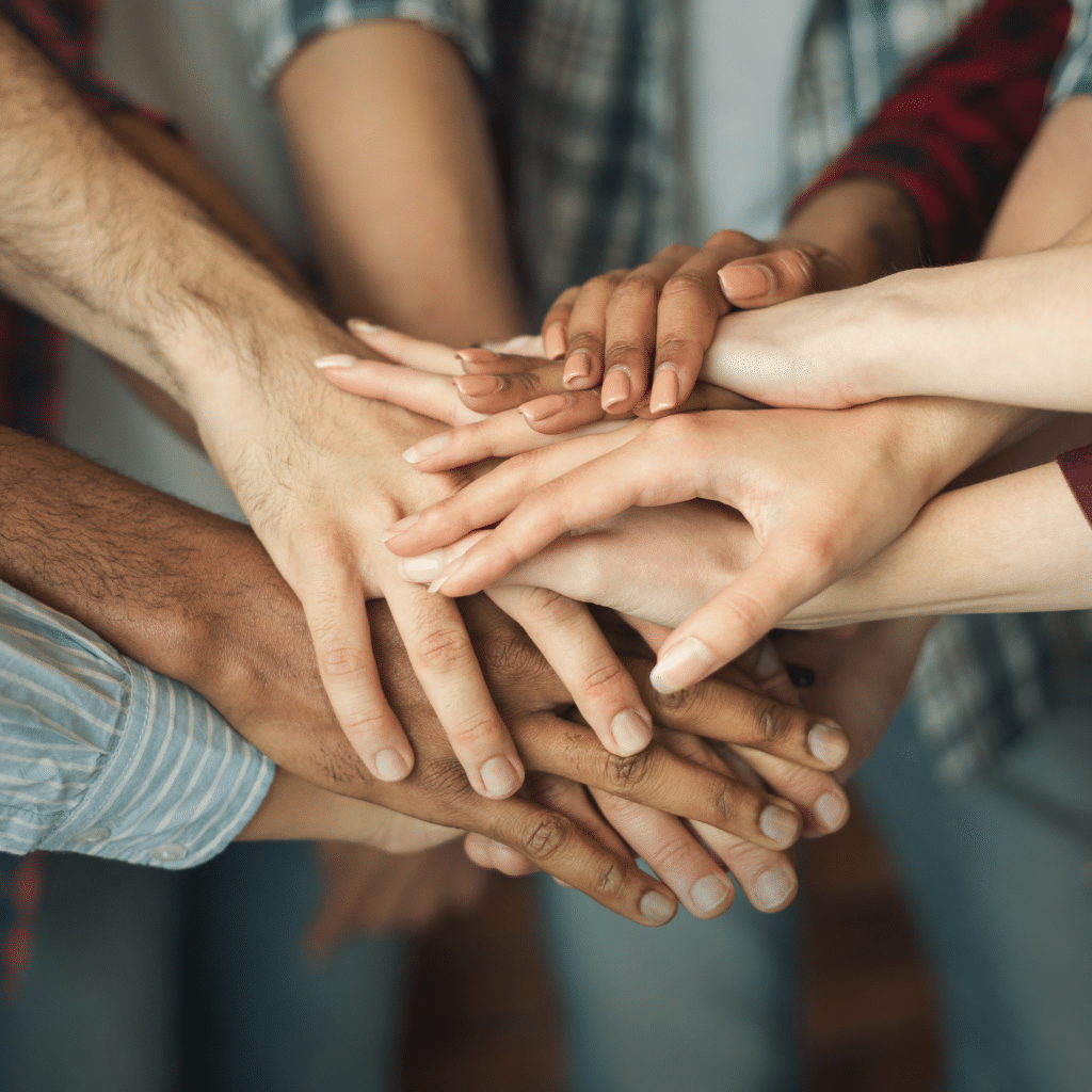 Equipo con manos entrelazadas, simbolizando la unidad y la colaboración en Unión por el Bienestar.