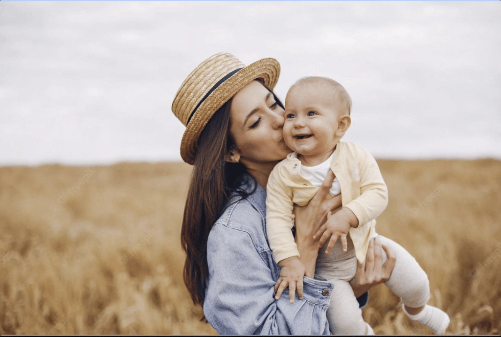 Madre sonriendo con su bebé en brazos, reflejando el bienestar y la felicidad en Unión por el Bienestar."